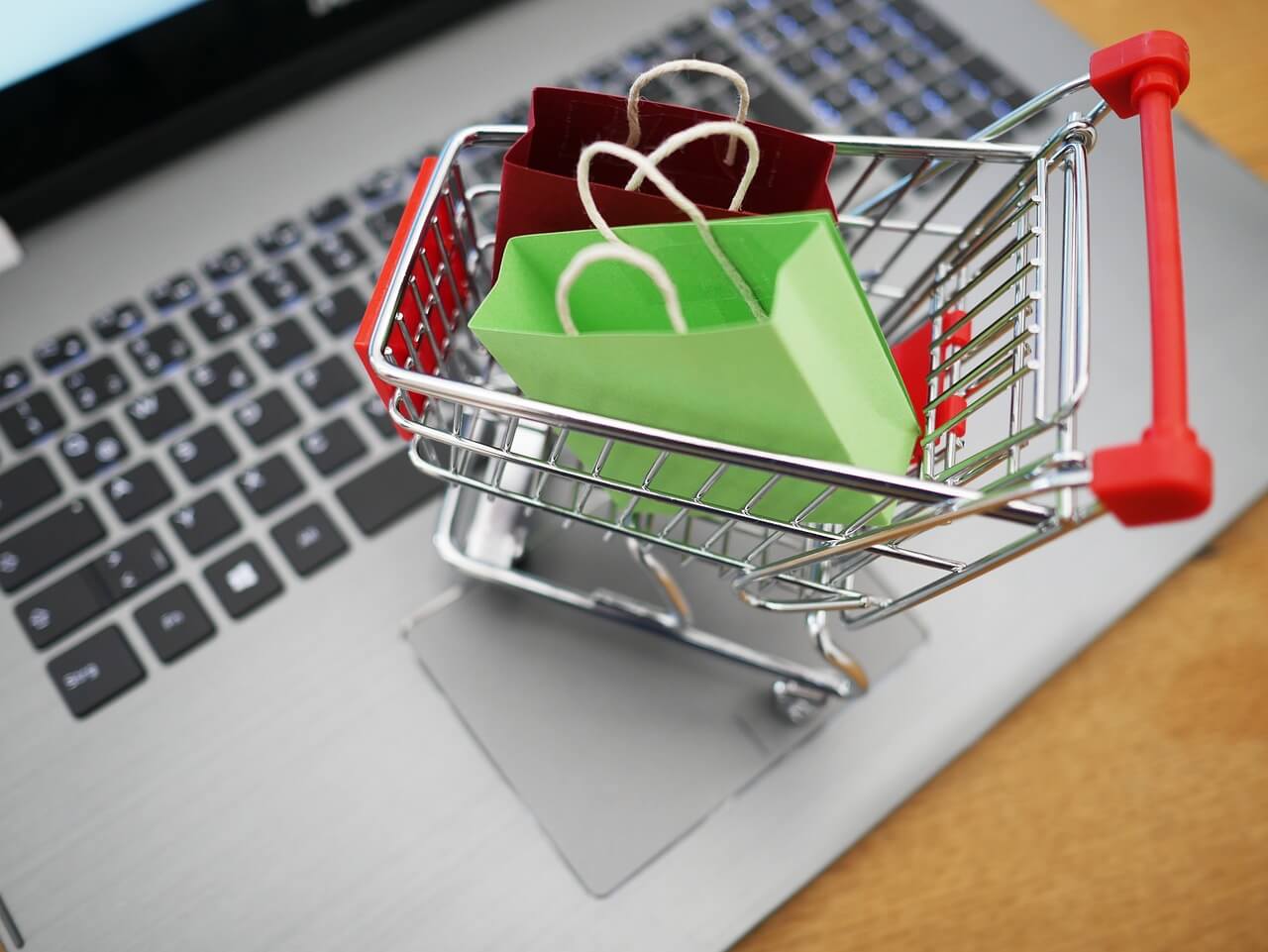 Shopping trolley and laptop representing digital and physical retail.